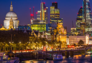 An evening, brightly-lit view of St. Paul's Cathedral and other buildings in the city of London