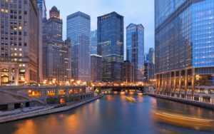 A photo from the Michigan Avenue Bridge over the Chicago River showing buildings in downtown Chicago at dusk